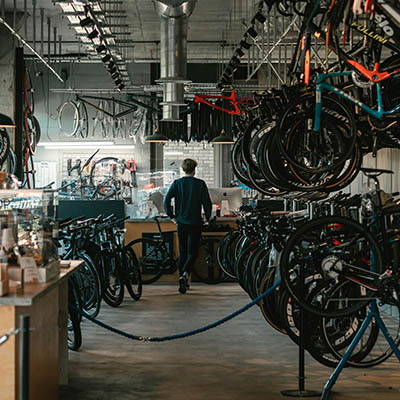 how the inside of spokes and saddles store looks, with rows of bikes, some mounted above with a path to walk in the middle and a man at the end of the path with his backtowards us